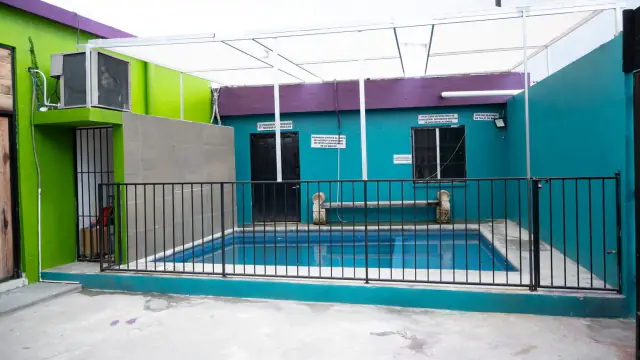 La alberca de Playland, techada con lona blanca y cercada con reja, entre paredes verdes y turquesa