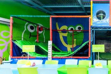 Dos camas elásticas de Playland con malla de seguridad y las ranas de la marca pintadas al fondo