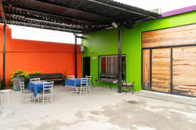 Patio techado de Playland con asadores, mesas de mantel azul y series de foquitos