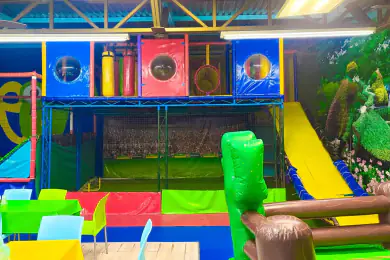 La estructura de juegos de Playland con sus ventanas circulares y sacos colgantes, la resbaladilla amarilla y la cancha al fondo