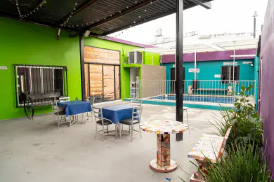 Terraza de Playland con mesas altas y sombra de pérgola, y la alberca al fondo